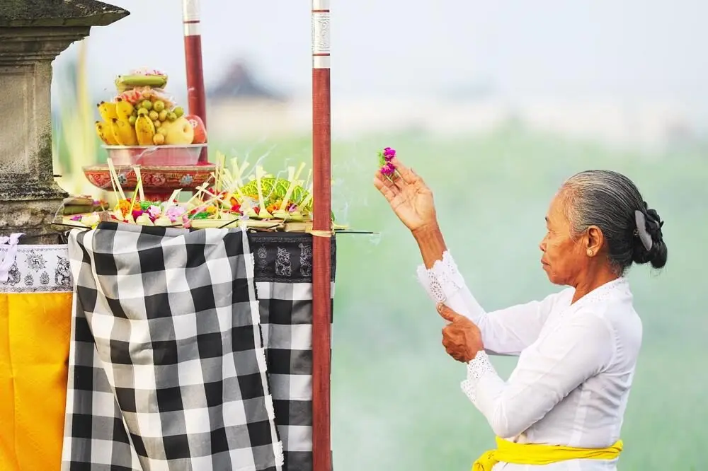 Balinese woman praying at temple-1000x666